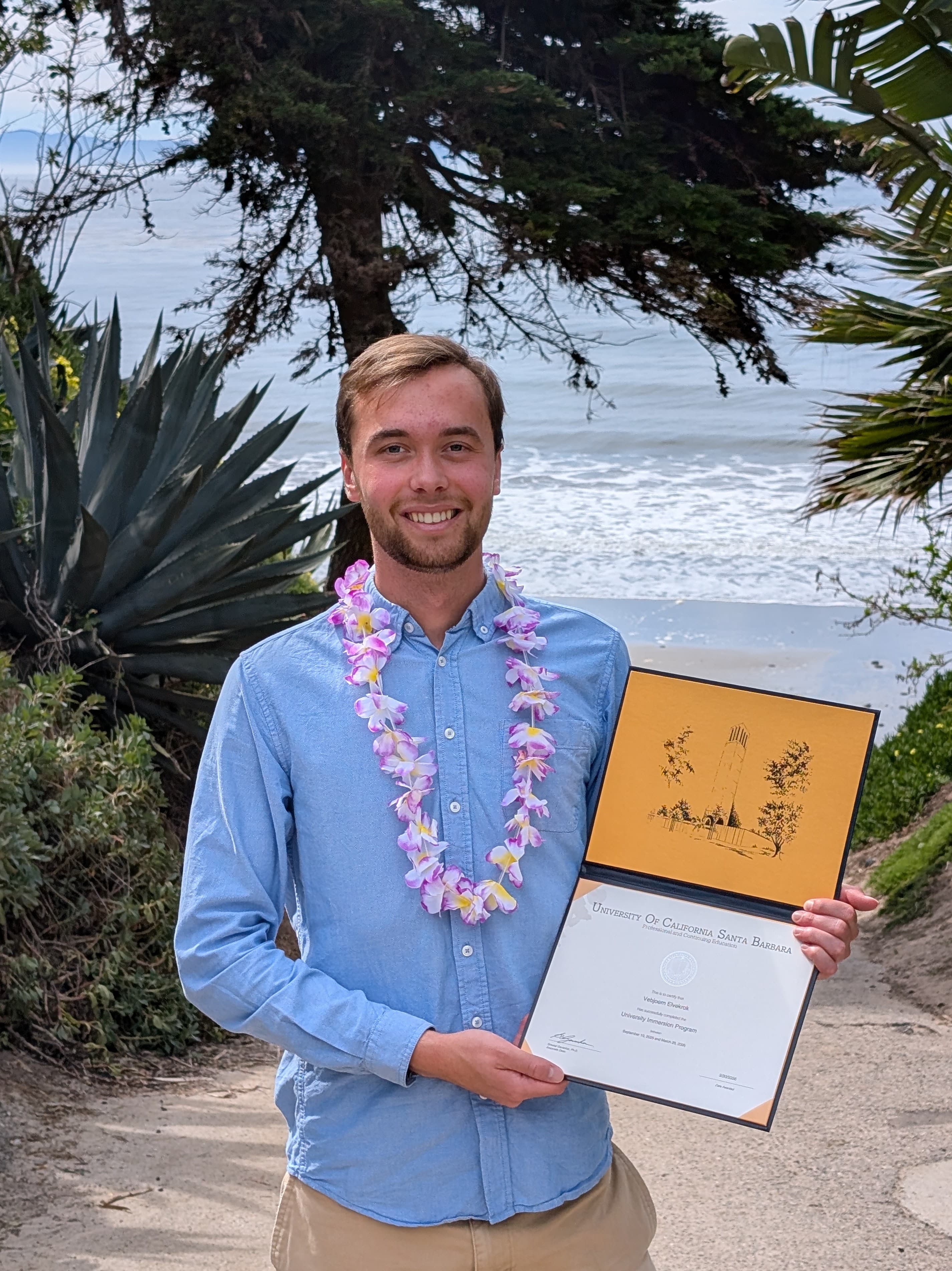 Vebjørn med diplomet frå UC Santa Barbara nede ved stranda